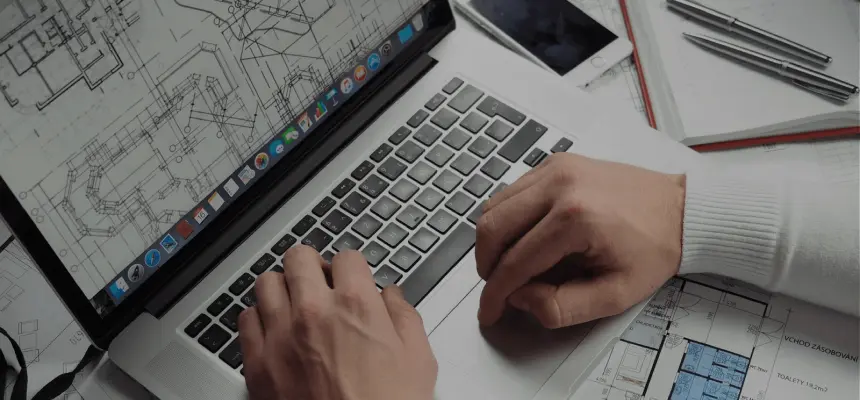 Looking down 'Over-the-shoulder' view of hands on a laptop with an architectural schematic on screen